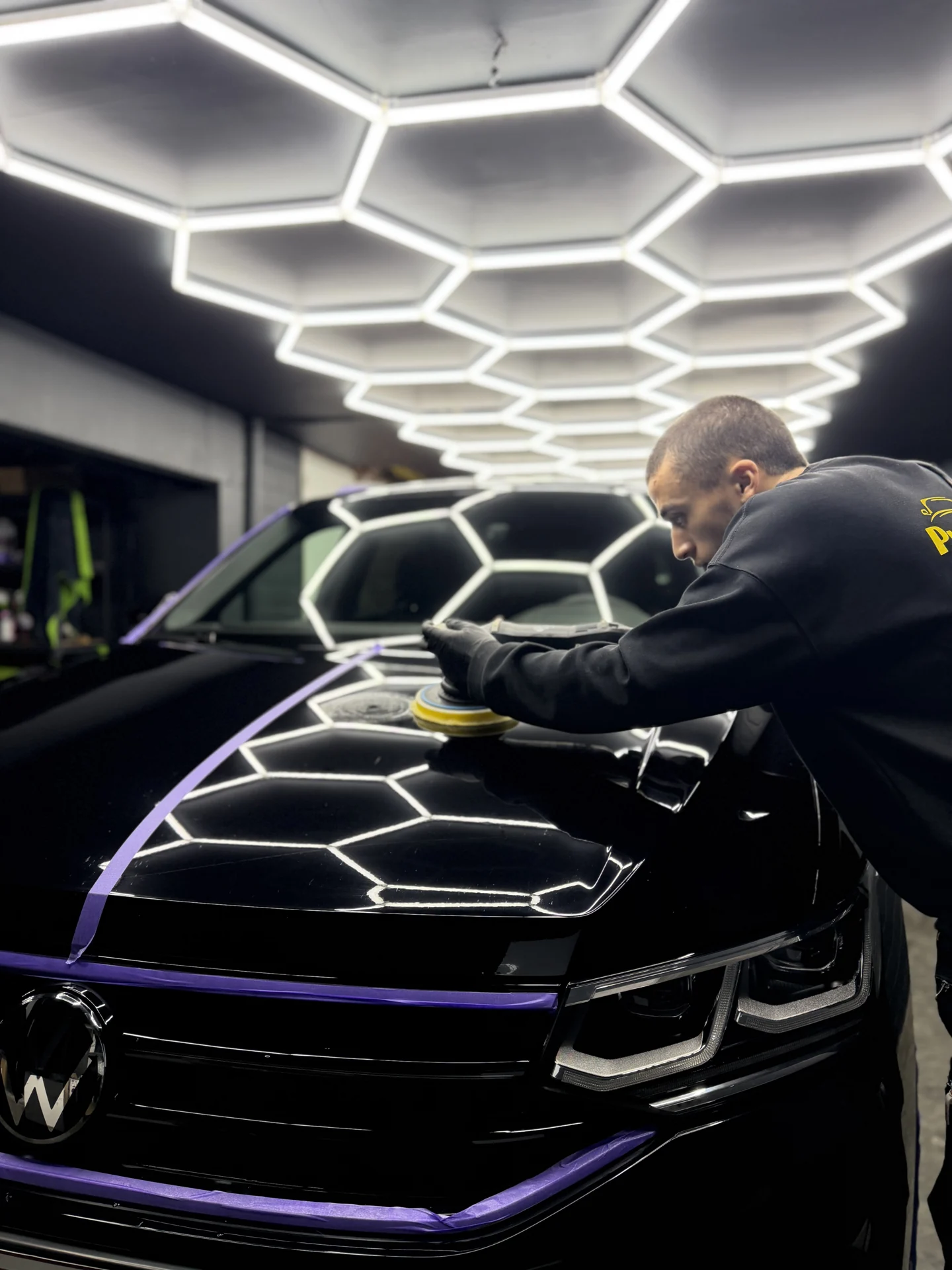 Achraf polijst een auto in de werkplaats van Prestige Car Care